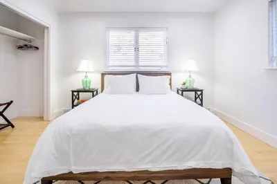 a white bedroom with a large white bed with two tables at Boulder Luxury Getaway 7 acres River & Pond in Boulder