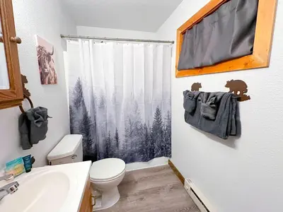 a bathroom with a toilet and a shower curtain with trees at Grand Lake Haven in town, Osprey Studio Cabin in Grand Lake