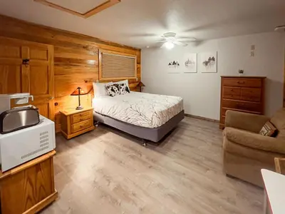 a bedroom with a bed and a tv and a couch at Cozy cabin Steps from Lake and Board walk, 5 min RMNP, Moose Lodge Studio in Grand Lake