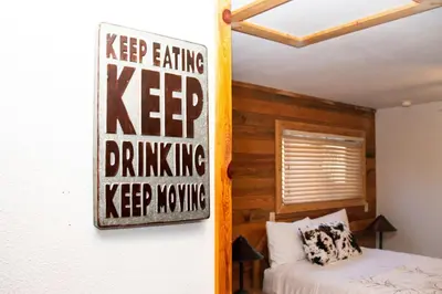 a bedroom with a keep drinking keep nesting sign on the wall at Cozy cabin Steps from Lake and Board walk, 5 min RMNP, Moose Lodge Studio in Grand Lake
