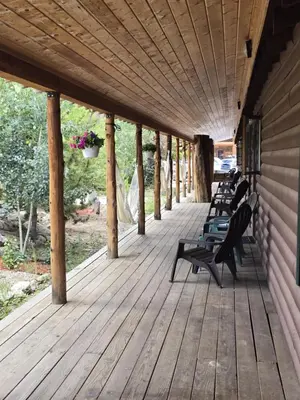 a row of benches sitting on a wooden porch at Cozy cabin Steps from Lake and Board walk, 5 min RMNP, Moose Lodge Studio in Grand Lake