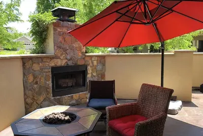 a patio with a fireplace and a red umbrella at The Fireside Retreat - 6 BD, Sauna, Home Theater in Greeley