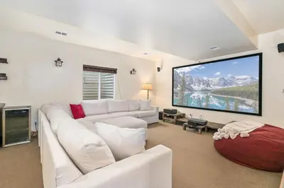 a living room with a white couch and a large screen at The Fireside Retreat - 6 BD, Sauna, Home Theater in Greeley
