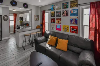 a living room with a leather couch and a kitchen at groovy apartment in the heart of the city in Denver