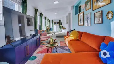 a living room with an orange couch and a tv at 15min to Denver - AirHockey - Arcade - Minigolf - Sleeps10 in Westminster