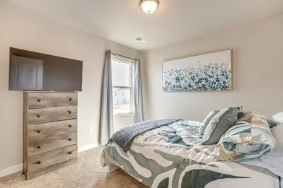 a bedroom with a bed and a dresser with a television at Beautiful Home with Bonus Room and Prime Location! in Brighton