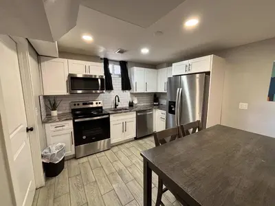 a kitchen with white cabinets and a table and a refrigerator at Gorgeous 2-King-Bed Lower Unit in Denver in Denver