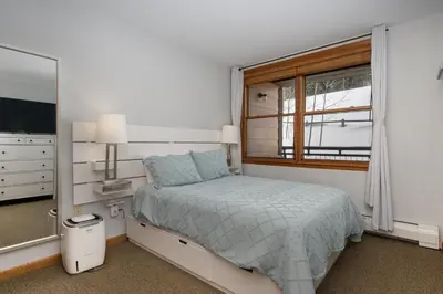 a white bedroom with a bed and a window at Premium Unit 1305 - Zephyr Mountain Lodge condo in Winter Park