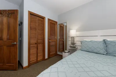 a bedroom with a large bed and wooden doors at Premium Unit 1305 - Zephyr Mountain Lodge condo in Winter Park