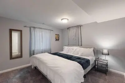 a bedroom with a large white bed with a window at Bright basement unit with large yard and sunroom in Denver