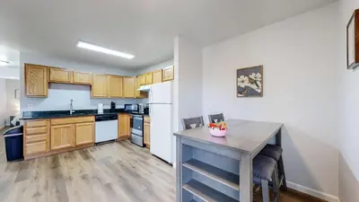 a kitchen with wooden cabinets and a table with chairs at Spacious two bedroom apartment near DIA in Brighton