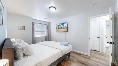 a white bedroom with a bed and a window at Spacious two bedroom apartment near DIA in Brighton