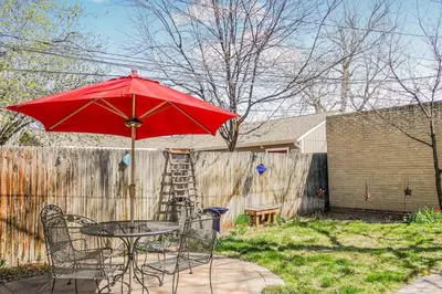 a table and chairs with a red umbrella in a yard at Charming two bedroom family home in coveted neighborhood in Denver