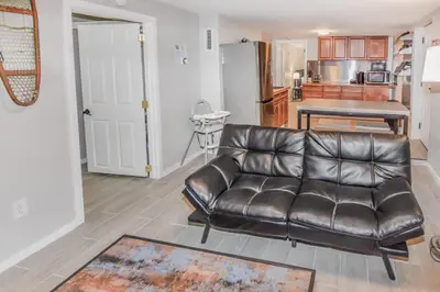 a leather couch in a living room with a kitchen at Cozy two bedroom basement unit near light rail in Denver