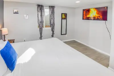 a white bedroom with a large white bed with a blue pillow at Cozy two bedroom basement unit near light rail in Denver