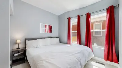 a bedroom with a bed and a window with red curtains at Spooky Victorian Family house with four bedrooms central to downtown in Denver