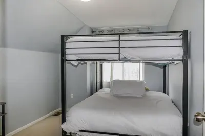 a bedroom with a bunk bed with white sheets at Charming Family Home with Cozy Retreat in Denver