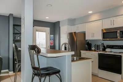 a kitchen with white cabinets and a black chair in it at Charming Family Home with Cozy Retreat in Denver