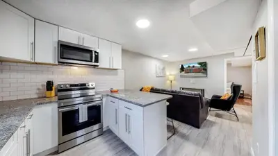 a kitchen with a stove top oven next to a living room at Cozy Lower Unit Retreat in Denver in Denver