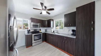 a kitchen with wooden cabinets and a ceiling fan at Bright & Spacious Upper Unit with Two Bedrooms in Denver in Denver