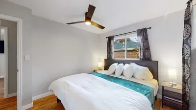a bedroom with a white bed with a ceiling fan at Spacious Family Retreat in Denver in Denver