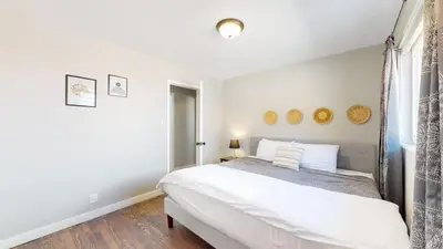 a white bedroom with a bed and a window at Stunning Upper Family Unit with King Beds & Yard in Denver