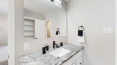 a white bathroom with a sink and a mirror at Stunning Upper Family Unit with King Beds & Yard in Denver