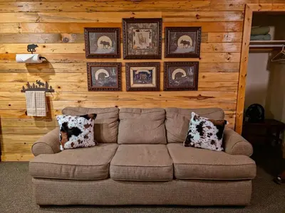 a couch in a living room with pictures on the wall at Kinnikinnick Retreat Steps from the Lake and Board walk, 5 min drive to RMNP. in Grand Lake
