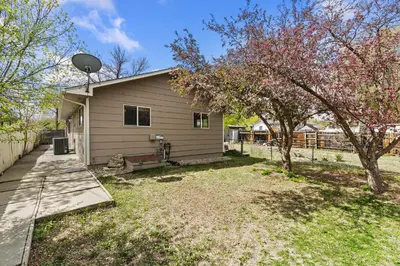 a house with a fence and trees in the yard at Old Town Basecamp 6 Blocks to Old Town Square in Fort Collins