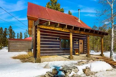 a log cabin with a red roof in the snow at Shadow Mountain Marina in Grand Lake
