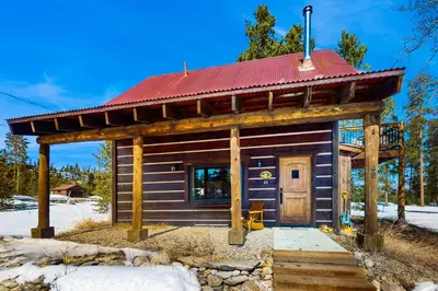 a small log cabin with a red roof at Shadow Mountain Marina in Grand Lake