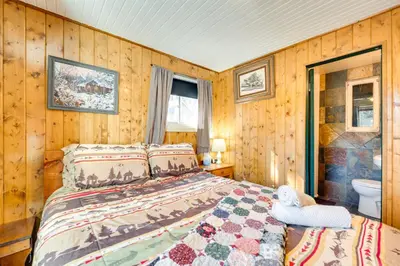 a bedroom with a bed in a room with wooden walls at Private Hot Tub and Deck Riverfront Escape in Drake in Drake