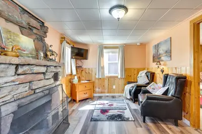 a living room with a stone fireplace and two chairs at Private Hot Tub and Deck Romantic Getaway in Drake in Drake