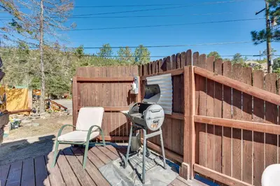 a fence with a camera and a chair on a deck at Fish, Hike and Unwind Drake Cabin with Hot Tub! in Drake