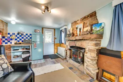 a living room with a stone fireplace and a couch at Fish, Hike and Unwind Drake Cabin with Hot Tub! in Drake