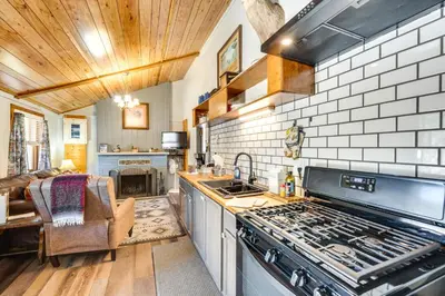 a kitchen with a stove top oven next to a couch at Private Hot Tub and Fishing On-Site Cabin in Drake in Drake