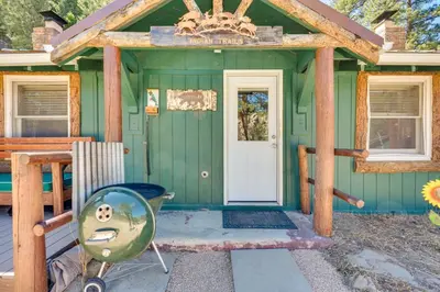a green house with a front door and a chandelier at Private Hot Tub and Fishing On-Site Cabin in Drake in Drake