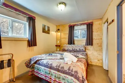 a bedroom with two beds and two windows at 4 Mi to Estes Park Riverfront Cabin with Hot Tub! in Drake