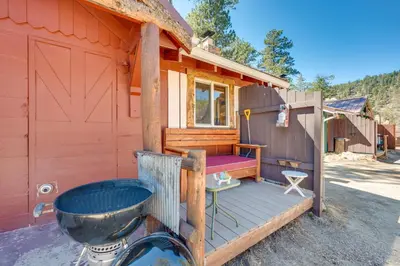 a front porch of a house with a grill at 4 Mi to Estes Park Riverfront Cabin with Hot Tub! in Drake