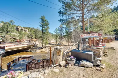 a small building next to a river with a bridge at 4 Mi to Estes Park Riverfront Cabin with Hot Tub! in Drake
