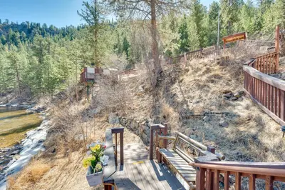 a wooden bridge over a river with trees at 4 Mi to Estes Park Riverfront Cabin with Hot Tub! in Drake
