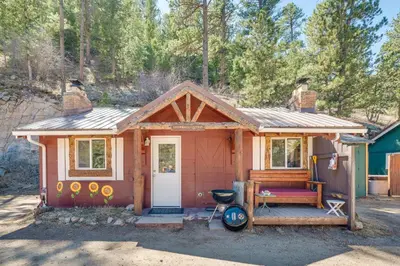 a tiny house with a porch and a grill at 4 Mi to Estes Park Riverfront Cabin with Hot Tub! in Drake