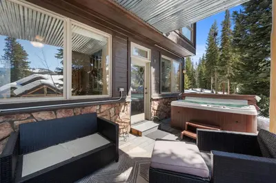 a screened in porch with a hot tub and chairs at 102 Mountain Lodge Way in Winter Park