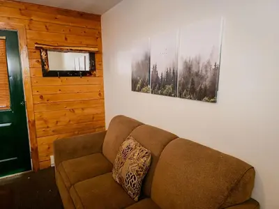 a couch in a living room with two pictures on the wall at Elk Run cabin steps to lake, In town, 5 min to RMNP in Grand Lake