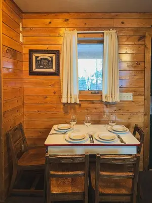 a dining room with a table with chairs and a window at Elk Run cabin steps to lake, In town, 5 min to RMNP in Grand Lake