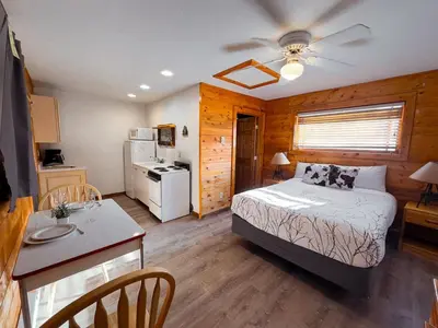 a bedroom with a bed and a kitchen with a table at Columbine Charming Cabin, 1 block from the lake, in town, 5 min to RMNP in Grand Lake