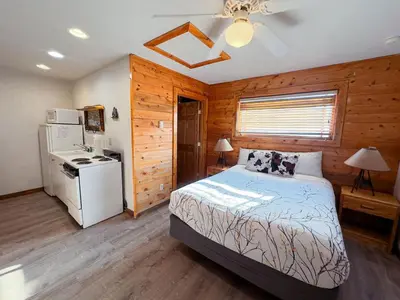 a bedroom with a bed and a refrigerator and a stove at Columbine Charming Cabin, 1 block from the lake, in town, 5 min to RMNP in Grand Lake