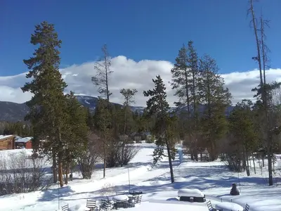 a snow covered field with chairs and trees in the distance at Colorado Cabin Adventure in Grand Lake