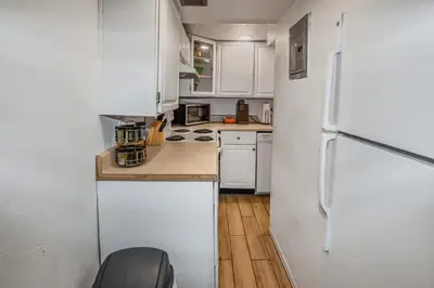 a kitchen with white cabinets and a white refrigerator at Cozy Mountain-Inspired Lower Unit in Denver in Denver