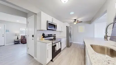 a white kitchen with a sink and a microwave at Bright & Cozy Upper Unit in Denver in Denver